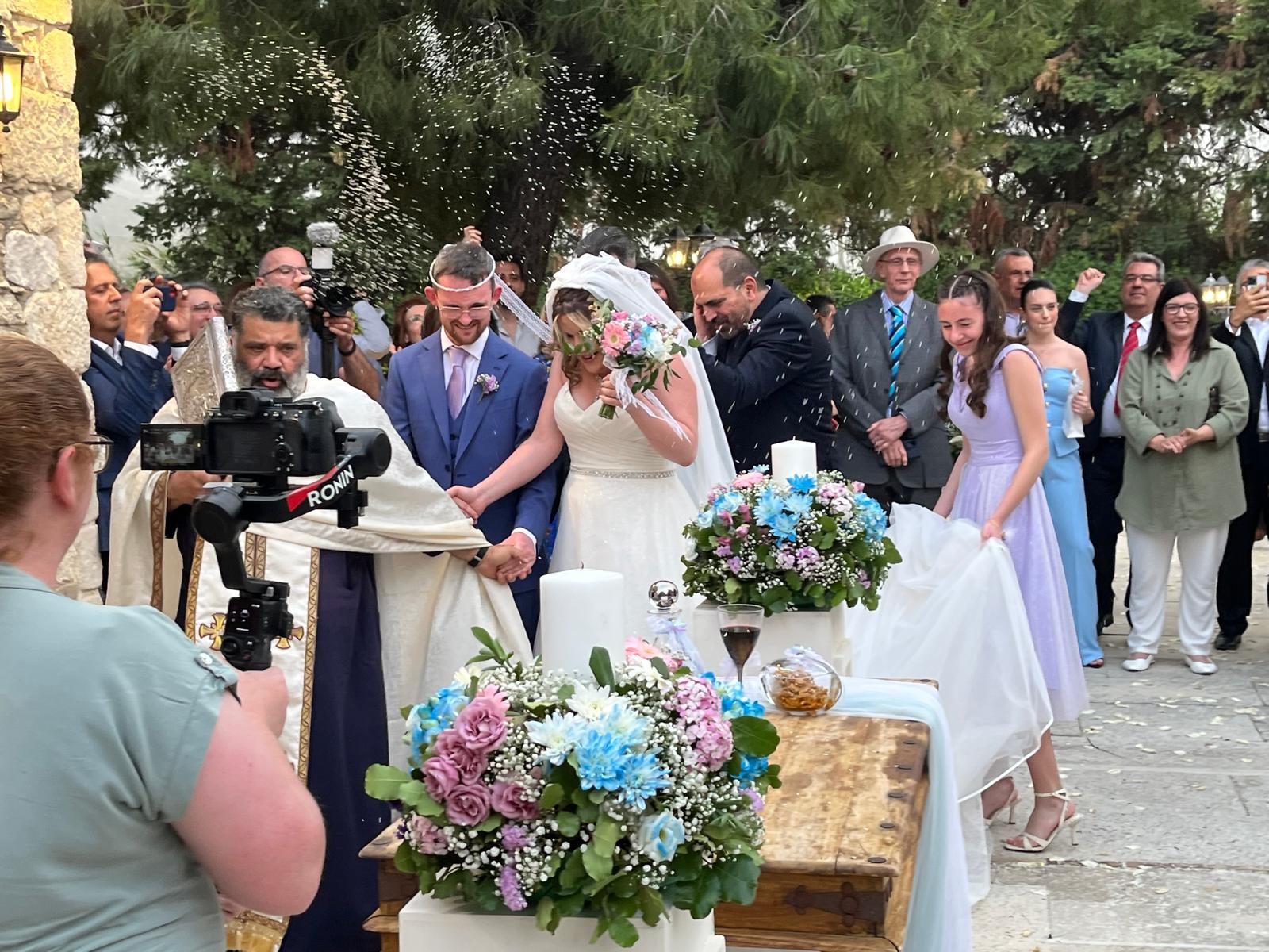 The couple and the priest rounding the table whilst being pelted with rice